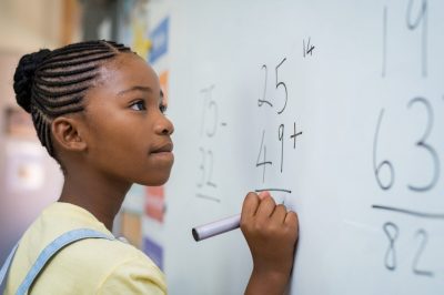 Girl student writing numbers on the whiteboard